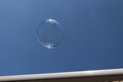 Low angle view of bubbles against blue sky 