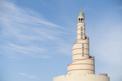 Low angle view of lighthouse by building against sky