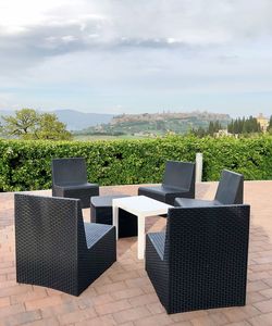 Empty chairs and tables in park against cloudy sky