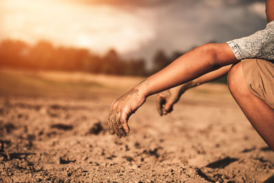 Midsection of man on sand at beach against sky