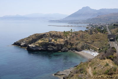 Scenic view of sea by mountains against sky