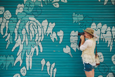 Woman photographing with camera against shutter