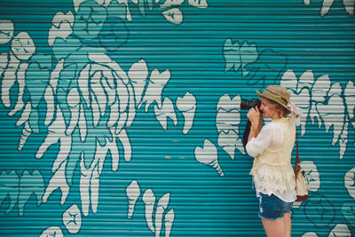 Full length of young woman standing against graffiti wall