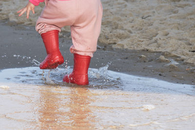 Low section of child standing on wet land