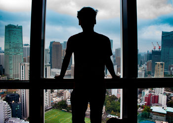 Rear view of silhouette man standing against buildings in city