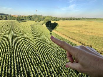 Midsection of person relaxing on field against sky