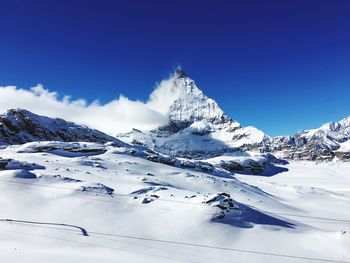 Scenic view of snowcapped mountains against blue sky