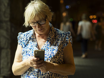 Mid adult woman using smart phone while standing outdoors