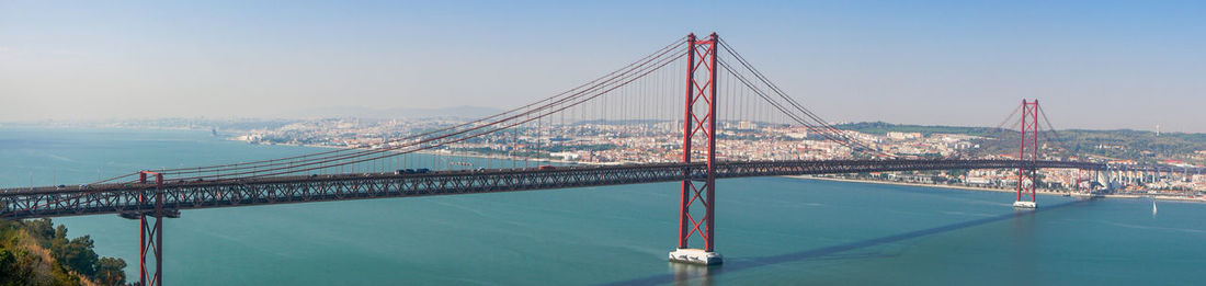 Suspension bridge in city against sky