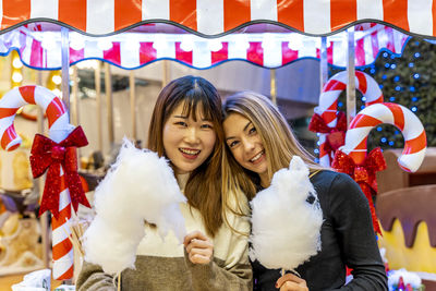 Couple of young multi-ethnic women eating cotton candy at a party. concept of millennial generation