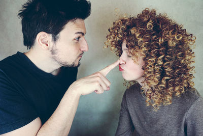Man touching woman nose against wall