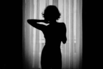 Shadow of woman standing against curtain