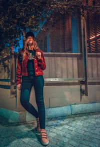 Portrait of young woman standing against building