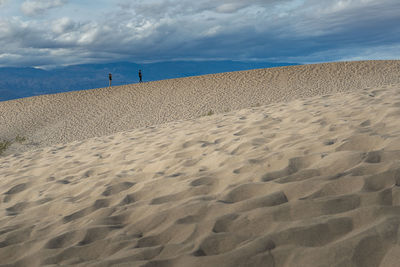 Footprints on sand at beach against sky