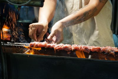 Midsection of man preparing food on barbecue grill