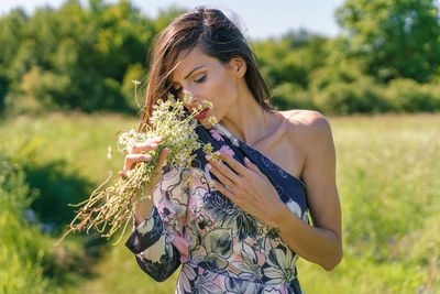 Midsection of woman holding plant on field