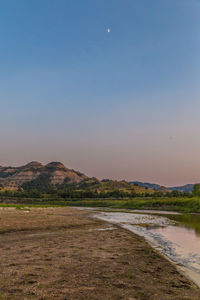 Scenic view of river by field against clear sky