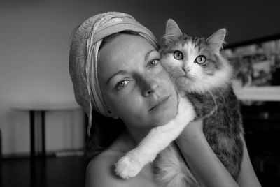 Close-up portrait of young woman with cat sitting at home