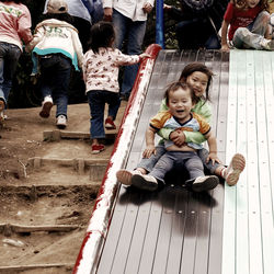 Siblings sliding on slide at park