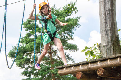 Adventure climbing high wire park - people on course in mountain helmet and safety equipment