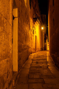 Narrow alley amidst buildings in city at night