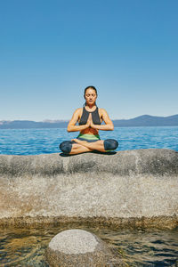Young woman practicing yoga on lake tahoe in northern california.