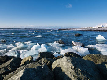 Rocks on beach against blue sky