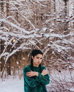 Portrait of young woman standing on snow covered tree
