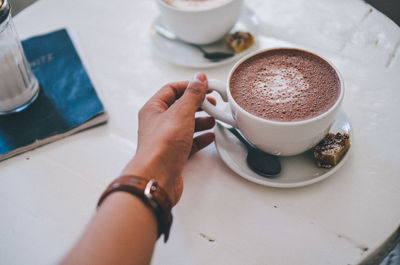 High angle view of woman holding coffee cup on table