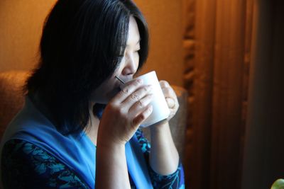 Woman drinking coffee while sitting at home