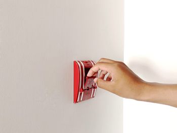 Close-up of woman hand holding red wall against white background