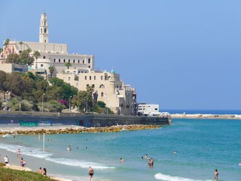 High angle view of people enjoying at beach against clear blue sky