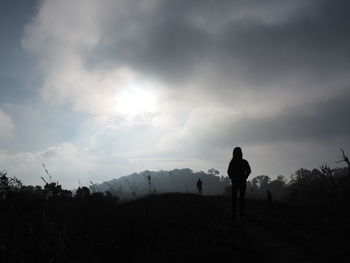 Rear view of silhouette people standing on field against sky