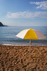 Bright yellow striped beach umbrella against the blue sky. beach vacation concept.