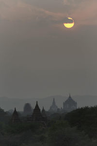 Temple amidst trees against sky at sunset