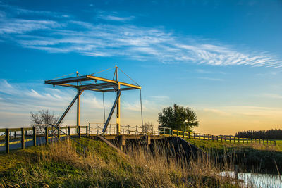 Windmill on field against sky during sunset