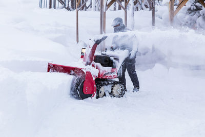 A man using snow blower to clear path in a public park