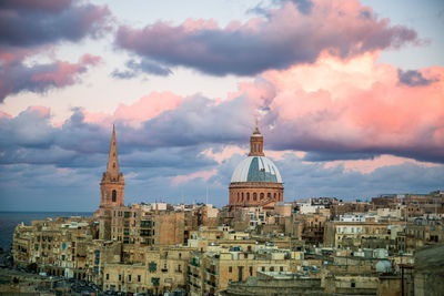 Buildings in city against cloudy sky