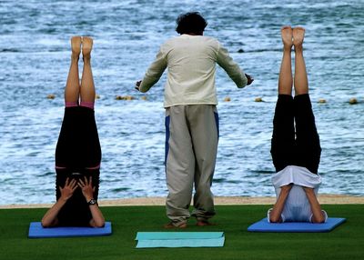 Rear view of people standing by sea