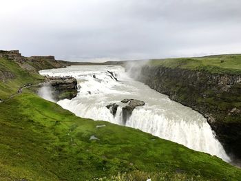 Scenic view of waterfall against sky