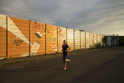 Rear view of woman running against wall