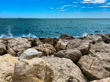 Rocks on beach against blue sky