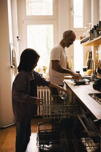 Father and son doing chores in kitchen at home