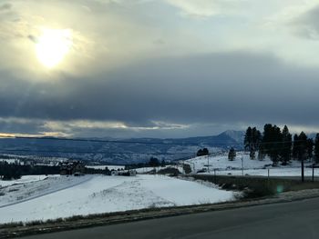 Snow covered road by landscape against sky