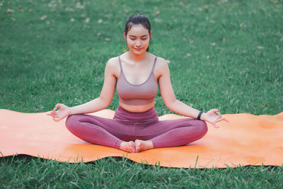 Full length of smiling woman sitting on field