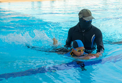 Instructor teaching swimming to boy in pool