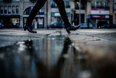 Low section of man walking on sidewalk in city during winter