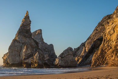 Rocks at sea shore against clear blue sky