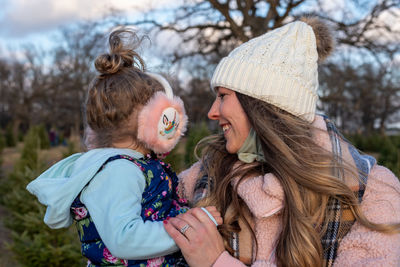 Smiling mother embracing with daughter while standing outdoors
