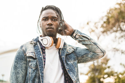 Portrait of young man with headphones standing in city